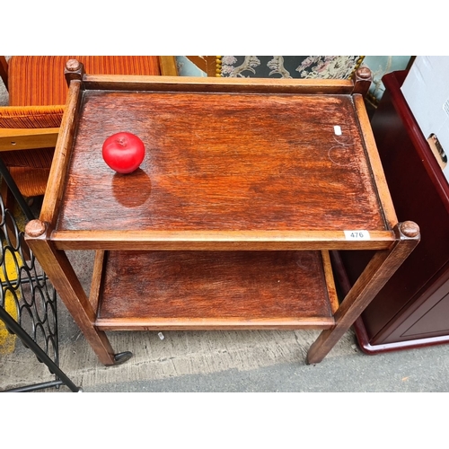 476 - Vintage wooden two-tier side table. Solid frame with rounded corners and castor wheels for mobility.