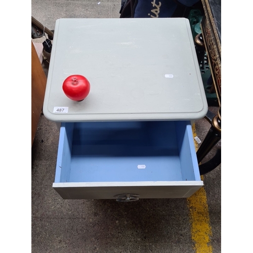 487 - A handsome  wooden nightstand with three drawers, featuring glass knobs and a unique red knob accent... 