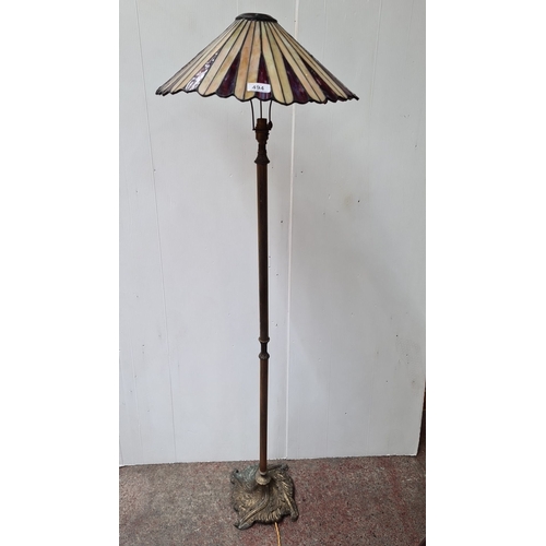 494 - Stained glass floor lamp with an ornate cast metal base featuring intricate leaf patterns. The lamp ... 