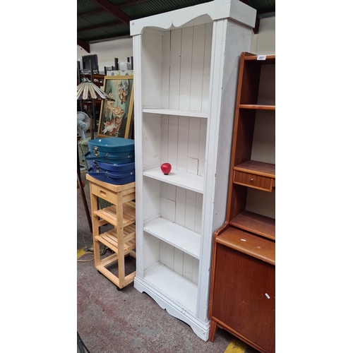 496 - White wooden bookshelf with four shelves, featuring a decorative top and vertical slats. Backside in... 