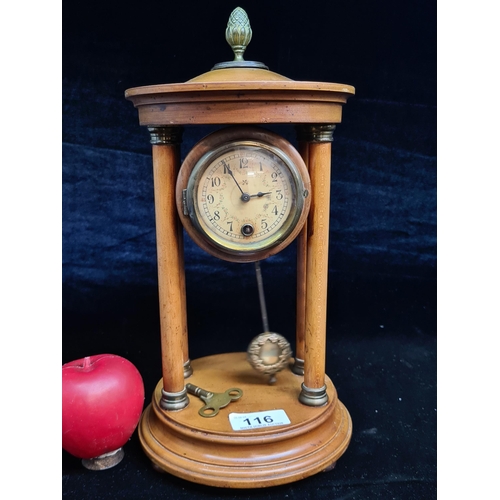 116 - A vintage wooden mantel clock featuring four columns, pendulum and acorn finial to top. Comes with p... 