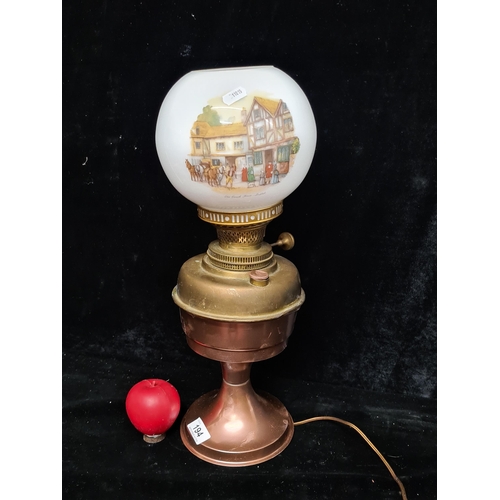 194 - A vintage brass and copper oil lamp featuring a milk glass painted shade.