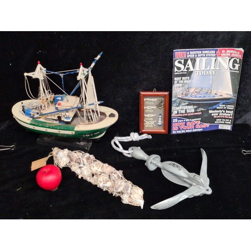 244 - A box containing nautical themed items including a wooden model fishing boat, a net of shells, frame... 