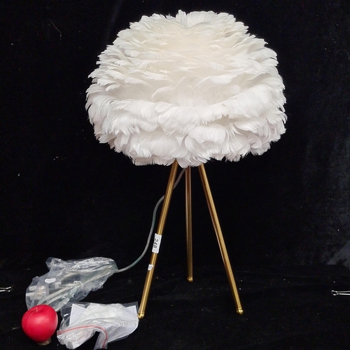 248 - A white feather table lamp on brushed brass tripod base. With original instructions for use and plug... 