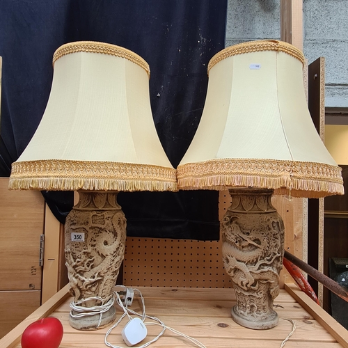 350 - A pair of stylish large ceramic table lamps with dragon motifs decorated in high relief.