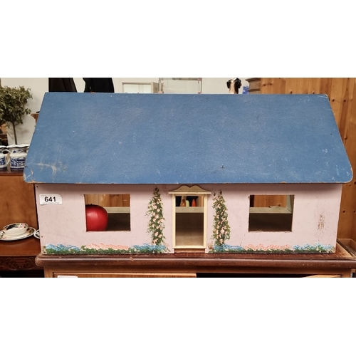 641 - Wooden dollhouse with painted brickwork and floral details, featuring a blue roof and pink exterior.... 