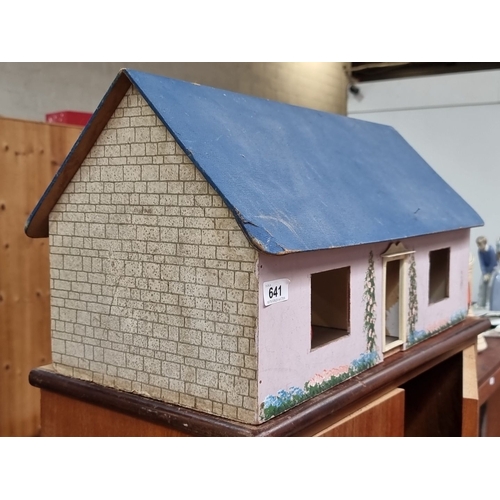 641 - Wooden dollhouse with painted brickwork and floral details, featuring a blue roof and pink exterior.... 