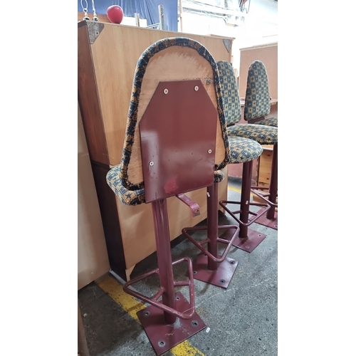 651 - Set of four retro bar stools featuring patterned upholstery and sturdy red metal bases.