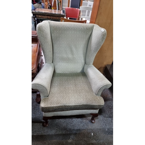 658 - High-back wing chair with patterned upholstery and cabriole legs in polished wood.