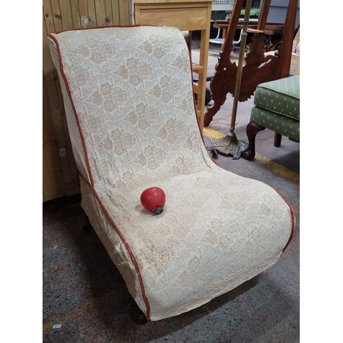 662 - Victorian slipper chair features a cream lace cover with scallop design, accented by a red trim and ... 