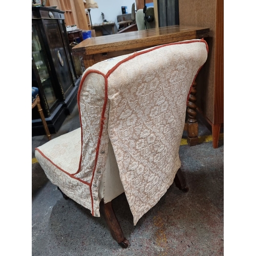 662 - Victorian slipper chair features a cream lace cover with scallop design, accented by a red trim and ... 