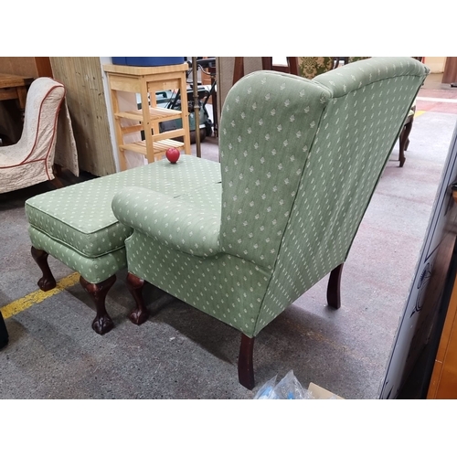 663 - Green upholstered wingback chair with matching ottoman. Features carved wooden cabriole legs and pat... 