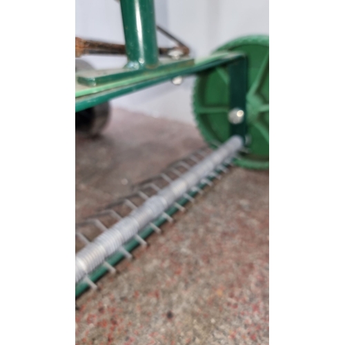 664 - Green and black metal frame with green wheels and green hopper. Metal spring mechanism is visible in... 