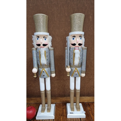 669 - Pair of glittery nutcracker figures, each standing around 12 inches tall, in silver and gold attire ... 