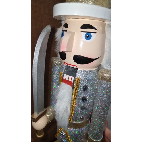 669 - Pair of glittery nutcracker figures, each standing around 12 inches tall, in silver and gold attire ... 