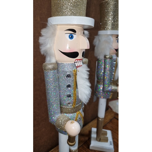 669 - Pair of glittery nutcracker figures, each standing around 12 inches tall, in silver and gold attire ... 