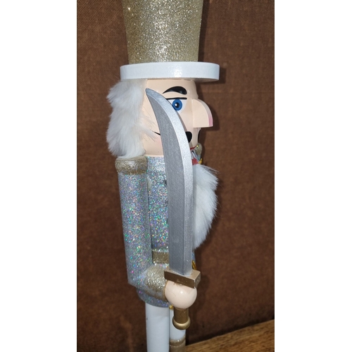 669 - Pair of glittery nutcracker figures, each standing around 12 inches tall, in silver and gold attire ... 