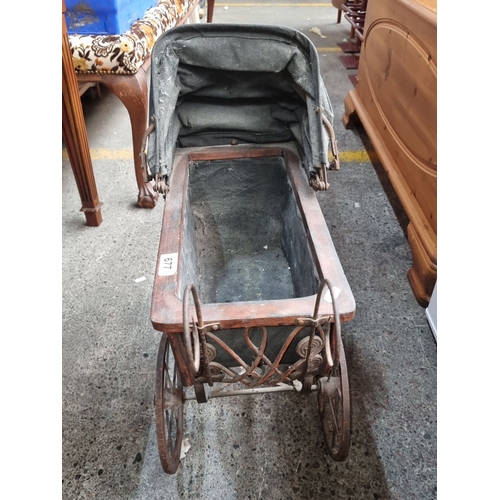 677 - An Antique Wrought iron baby carriage from the Victorian era with an intricately designed metal fram... 