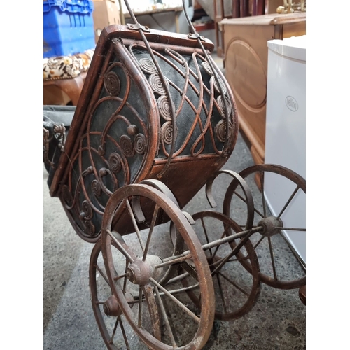 677 - An Antique Wrought iron baby carriage from the Victorian era with an intricately designed metal fram... 