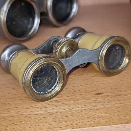 687 - Pair of vintage brass opera glasses. One with bone-colored barrels and the other with faded blue cov... 