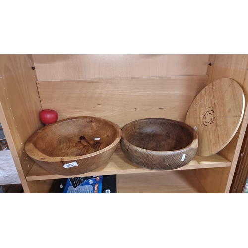 692 - Set of three wooden bowls made from solid wood with visible grain patterns, varying in color from li... 