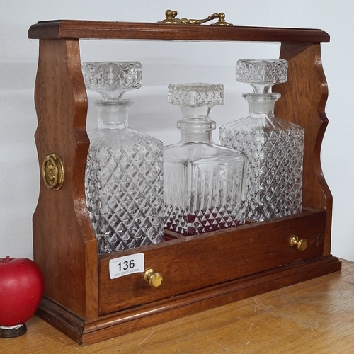 136 - A vintage tantalus with three crystal decanters, plush red interior and brass detailing.