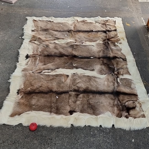 802 - Star lot : A very large Reindeer hide rug features soft brown and white tones and an elegant natural... 