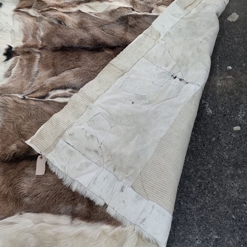 802 - Star lot : A very large Reindeer hide rug features soft brown and white tones and an elegant natural... 