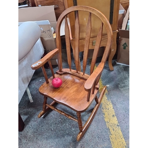 1384 - A charming children's wooden rocking chair with spindle backrest and armrests, made from hardwood.
P... 