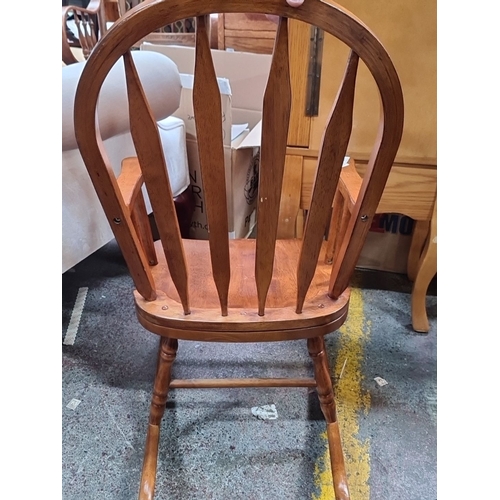 1384 - A charming children's wooden rocking chair with spindle backrest and armrests, made from hardwood.
P... 