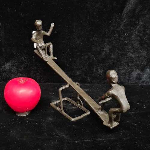 203 - A delightful metal sculpture depicting two young children playing on a seesaw.