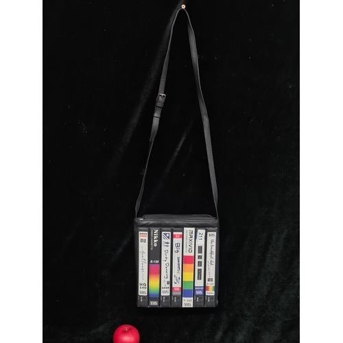 211 - A designer YOSHI Lichfield black crossbody bag featuring classic VHS tapes.