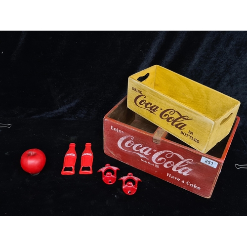 251 - Two Coca Cola branded wooden drinks crates with four cast iron wall mounted bottle openers. Brand ne... 