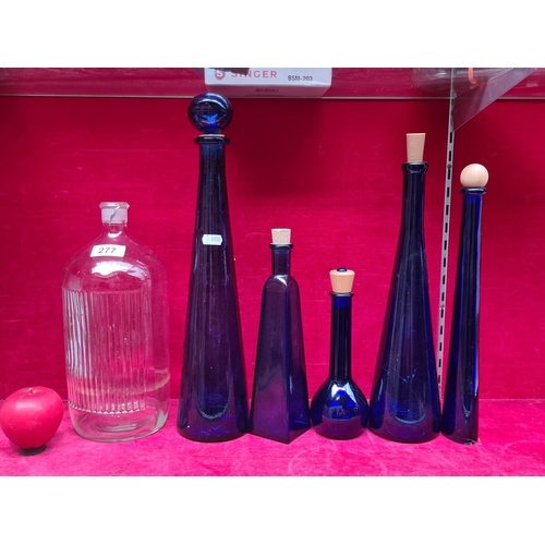 277 - Six glass bottles including five cobalt blue decanters in graduating sizes. Also includes a glass bo... 