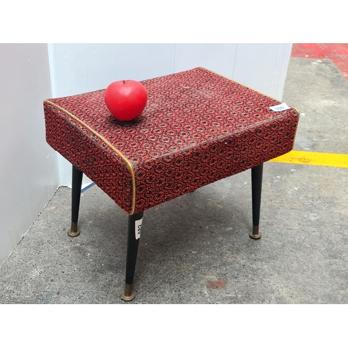 300 - A vintage foot stool. Upholstered in a deep red velvet fabric with Wegner legs ad brass base.