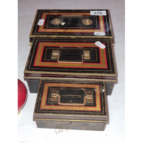 379 - Three vintage metal cash boxes, two with removable tray. All featuring gilt and red rectangular acce... 