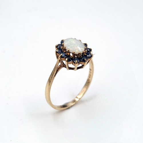 593 - Star Lot : A very pretty nine carat gold fire opal ring with sapphire cluster surround. Ring size - ... 