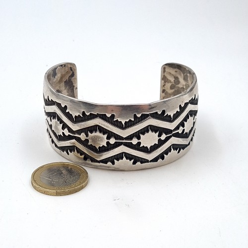 598 - A heavy silver bangle marked sterling with incised detailing. Weight - 61.85 grams.