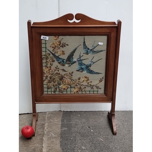 426 - A handsome Edwardian mahogany firescreen with embroidered panel depicting three swallow and flowers ... 