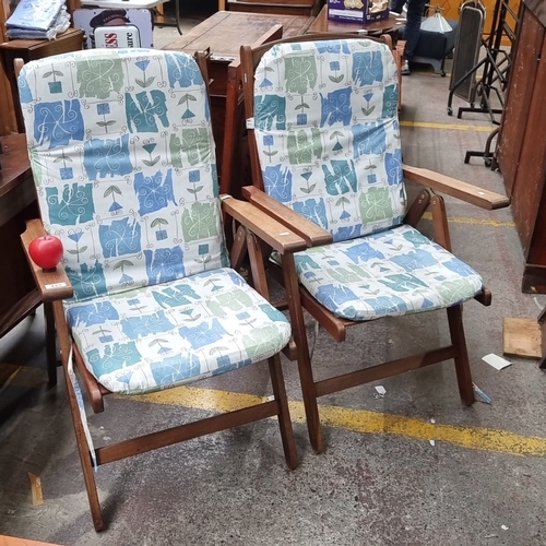 433 - Pair of teak fold up armchairs with adjustable backs, featuring patterned cushions in blue, green, a... 