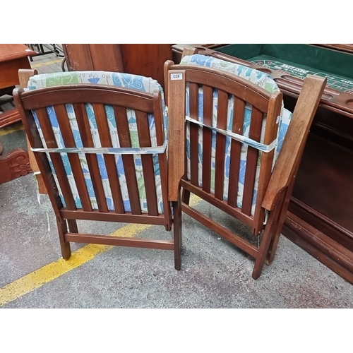 433 - Pair of teak fold up armchairs with adjustable backs, featuring patterned cushions in blue, green, a... 