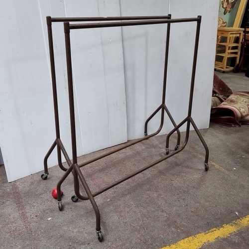 442 - Two vintage metal garment rack with hanging rails and caster wheels for mobility.