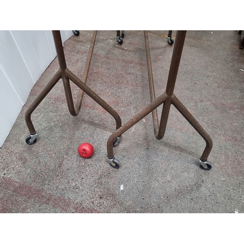 442 - Two vintage metal garment rack with hanging rails and caster wheels for mobility.