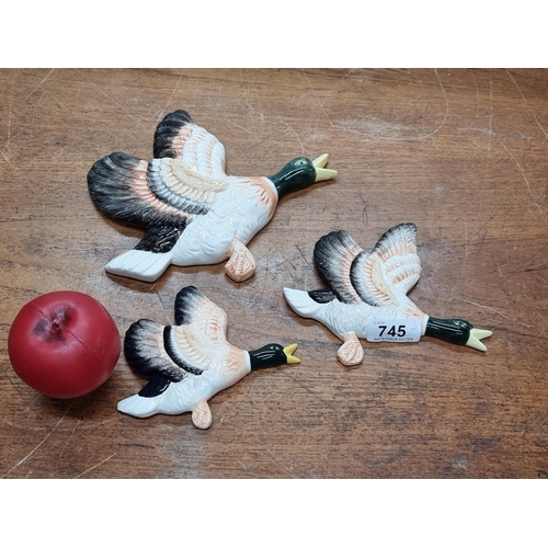 745 - A charming trio of graduating ceramic flying ducks.