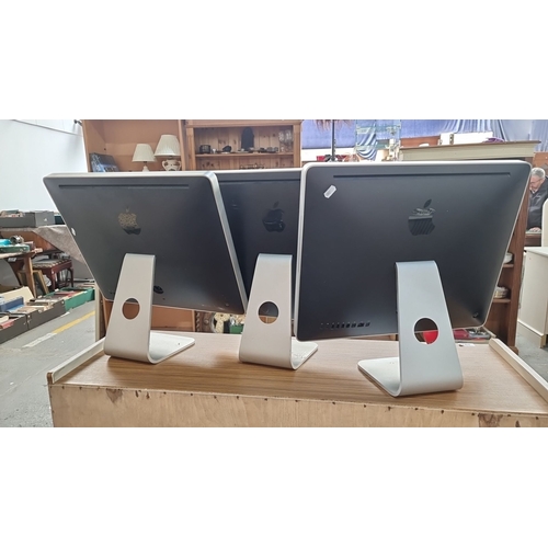 890 - Set of three Apple iMac desktop computers with 21-inch screens. Each features aluminum casings and b... 