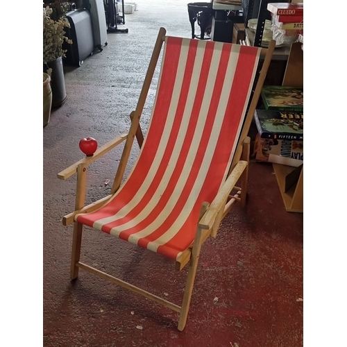 897 - Vintage wooden deck chair with red and white striped canvas seat. Classic outdoor furniture piece.