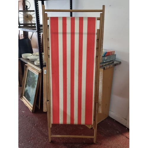 897 - Vintage wooden deck chair with red and white striped canvas seat. Classic outdoor furniture piece.