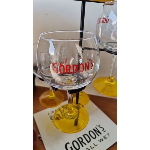 928 - Gordon's gin promotional rack with four branded glasses, featuring yellow stems and 'Shall we?' slog... 