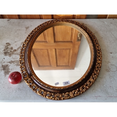 938 - Ornate oval mirror with a carved gold and dark wood frame, exhibiting Baroque Revival style detailin... 