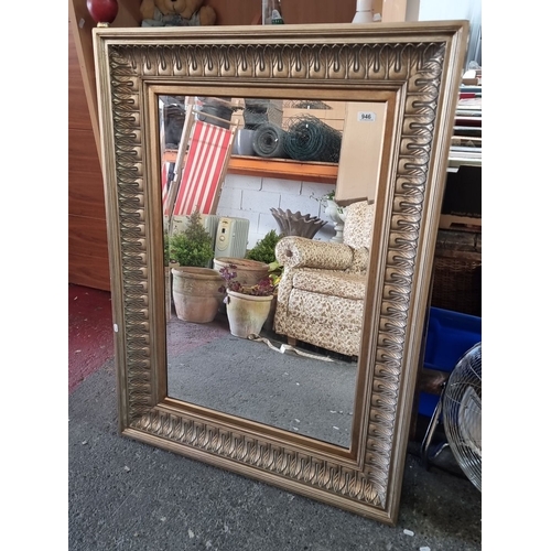 946 - Ornate gilded bevelled mirror with intricate leaf-patterned frame design, inspired by classical or V... 